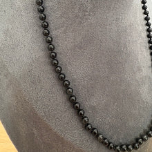 Load image into Gallery viewer, A black beaded necklace displayed on a grey velvet jewellery bust.