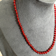 Load image into Gallery viewer, A red beaded necklace displayed on a grey fabric jewellery bust.