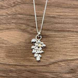 Sterling silver pendant offset with a singular 9ct gold bead. The pendant sits on a sterling silver curb chain and has a high polished finish.